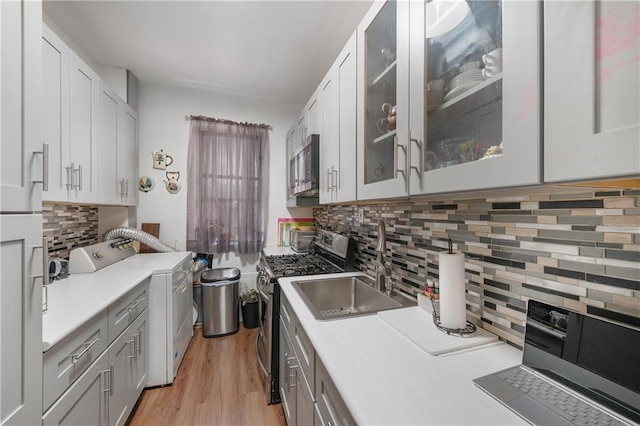 kitchen featuring white cabinets, light wood-type flooring, separate washer and dryer, and stainless steel appliances