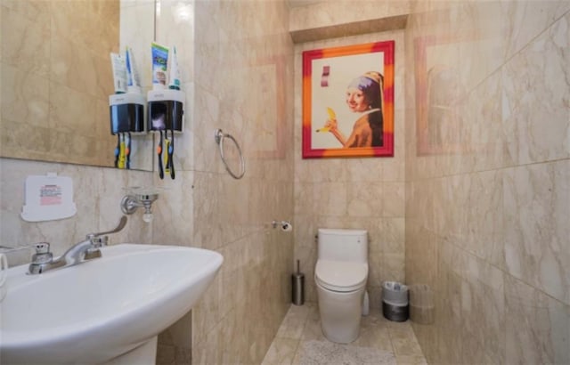 bathroom with tile walls, sink, tile patterned flooring, and toilet