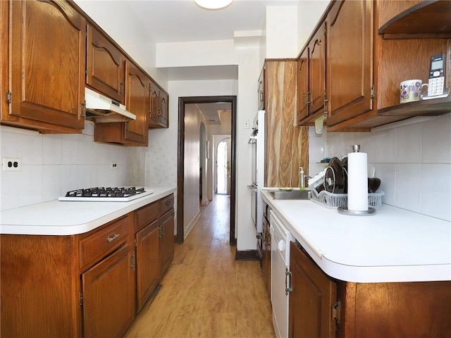 kitchen featuring white gas stovetop, premium range hood, sink, light hardwood / wood-style flooring, and decorative backsplash