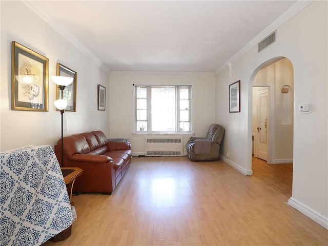 living room with radiator heating unit, light hardwood / wood-style flooring, and crown molding