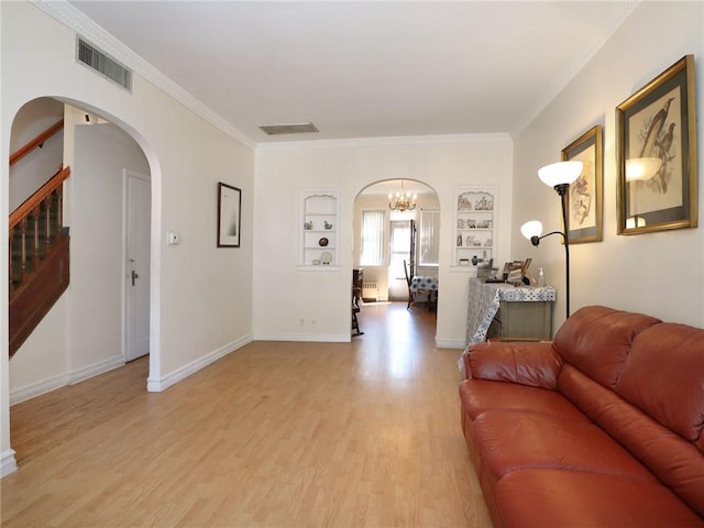 living room with light wood-type flooring, built in features, crown molding, and an inviting chandelier