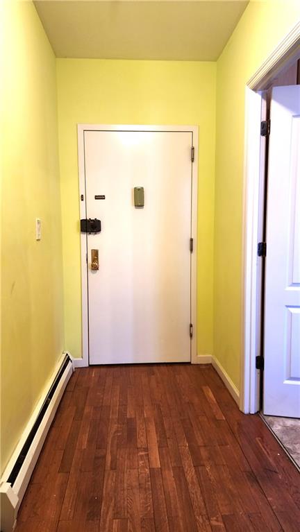 doorway to outside with dark hardwood / wood-style flooring and a baseboard heating unit