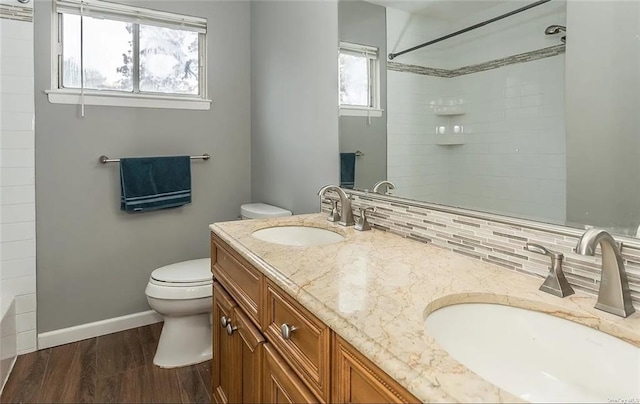 bathroom with toilet, decorative backsplash, hardwood / wood-style flooring, and vanity