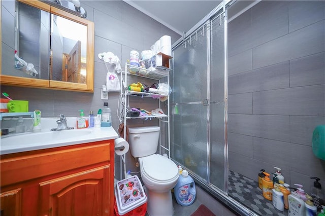 bathroom with vanity, toilet, tile walls, and a shower with shower door