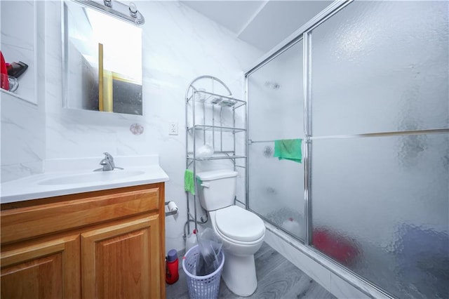 bathroom featuring toilet, a shower with door, vanity, and hardwood / wood-style flooring