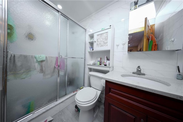 bathroom with backsplash, ornamental molding, vanity, toilet, and a shower with shower door