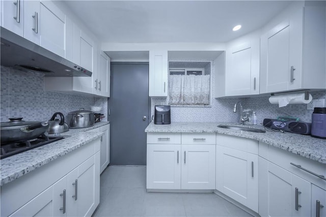 kitchen featuring tasteful backsplash, white cabinetry, and sink