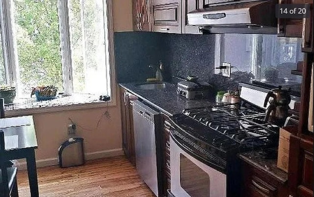 kitchen featuring wood-type flooring, sink, dark stone countertops, and stainless steel appliances