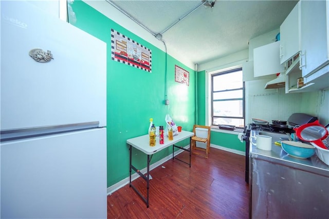 interior space featuring dark wood-style floors, baseboards, white cabinets, and freestanding refrigerator