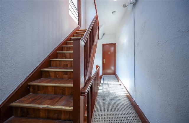 stairway with a textured wall and a high ceiling