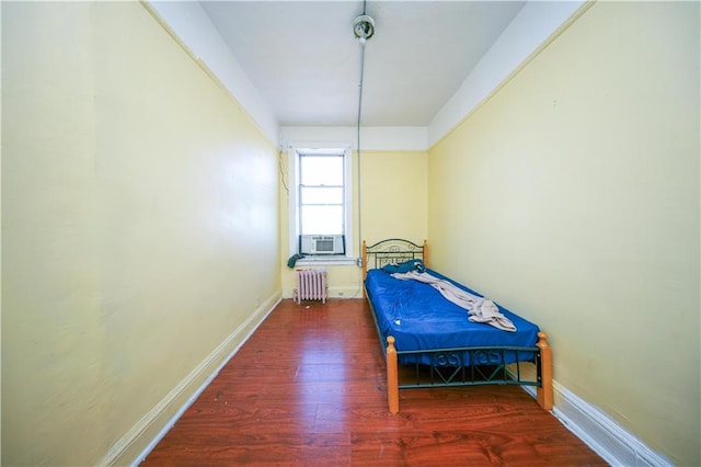 bedroom featuring baseboards, wood finished floors, radiator, and cooling unit
