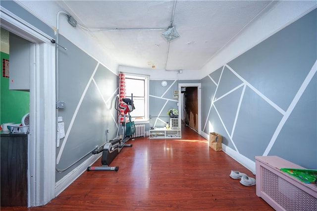 exercise room featuring radiator and wood finished floors