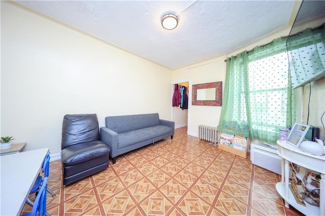 living area with radiator, a textured ceiling, and baseboards