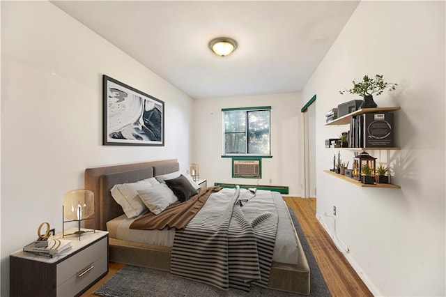bedroom with an AC wall unit and wood finished floors