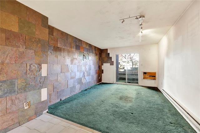 unfurnished room featuring track lighting, carpet, and a baseboard heating unit