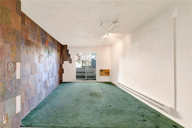 empty room featuring carpet, a baseboard heating unit, and track lighting