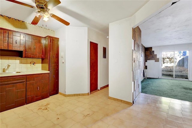 kitchen featuring ceiling fan, sink, light carpet, and backsplash