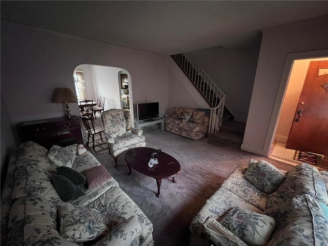 carpeted living area with arched walkways and stairs