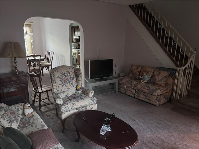 living area with arched walkways, carpet, and stairs