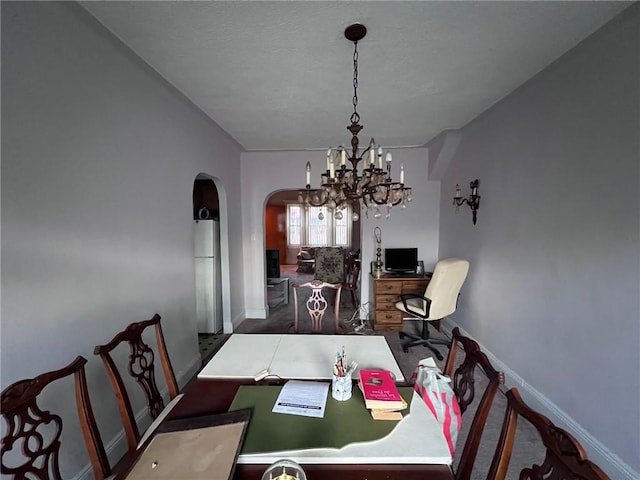 dining area with arched walkways, baseboards, and an inviting chandelier