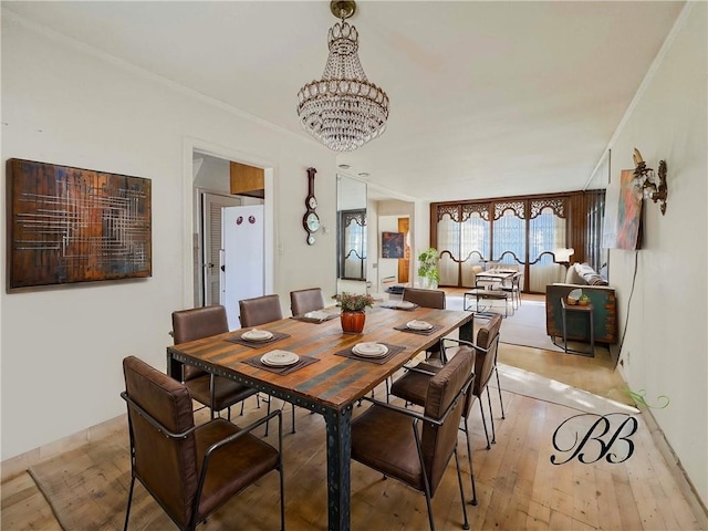 dining area with light wood-type flooring, a chandelier, and ornamental molding