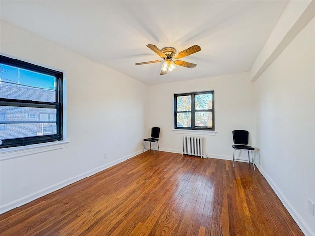 empty room featuring baseboards, radiator, ceiling fan, and hardwood / wood-style flooring