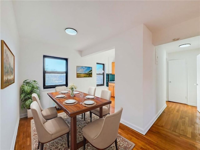 dining space with light wood-style flooring, plenty of natural light, and baseboards