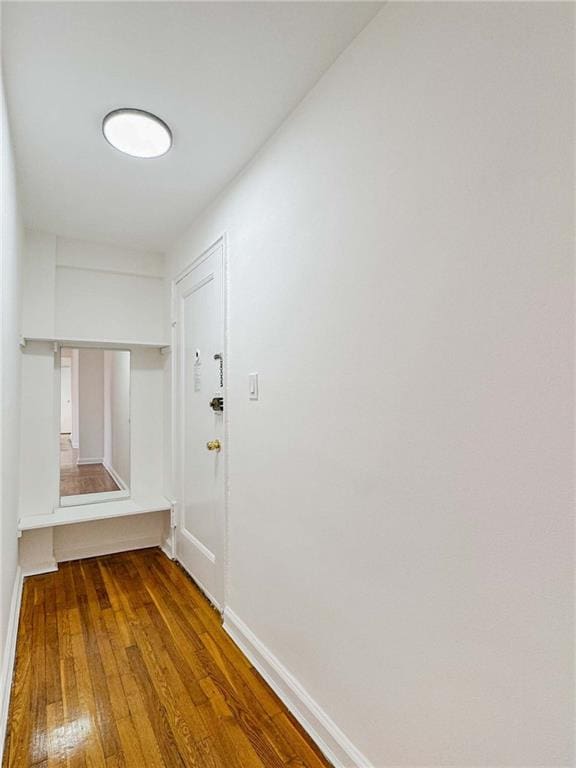 corridor with hardwood / wood-style floors and baseboards