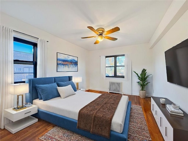 bedroom featuring baseboards, radiator heating unit, a ceiling fan, and wood finished floors