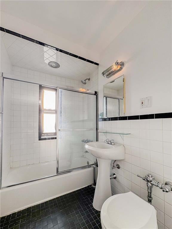 full bath with tile patterned floors, shower / bath combination with glass door, tile walls, and toilet