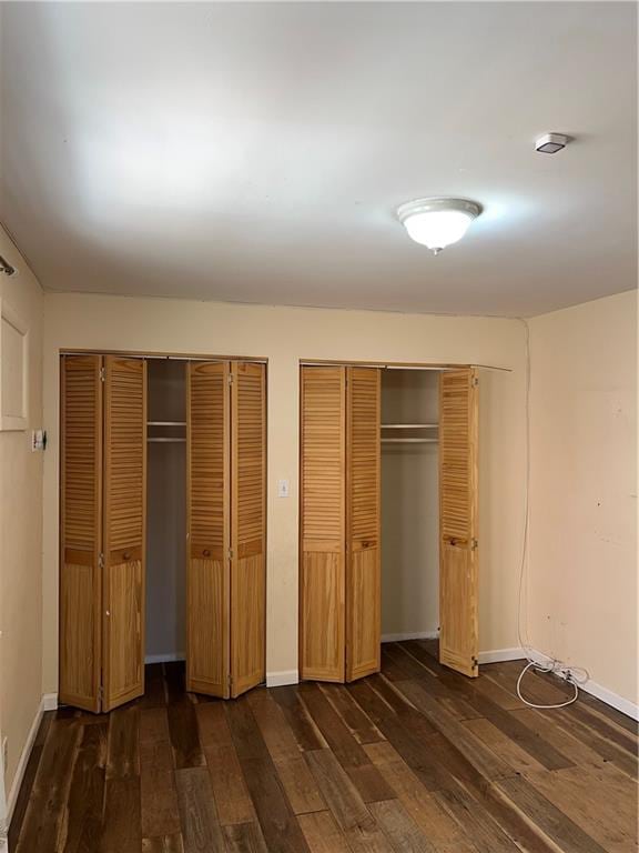 1044 E 96th St, Brooklyn, NY 11236 - unfurnished bedroom featuring two closets, dark wood-type flooring, and baseboards