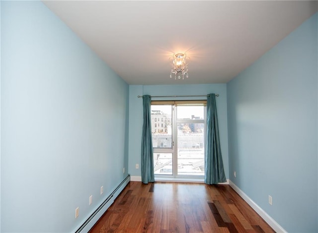 unfurnished room with hardwood / wood-style floors, a baseboard heating unit, and a chandelier