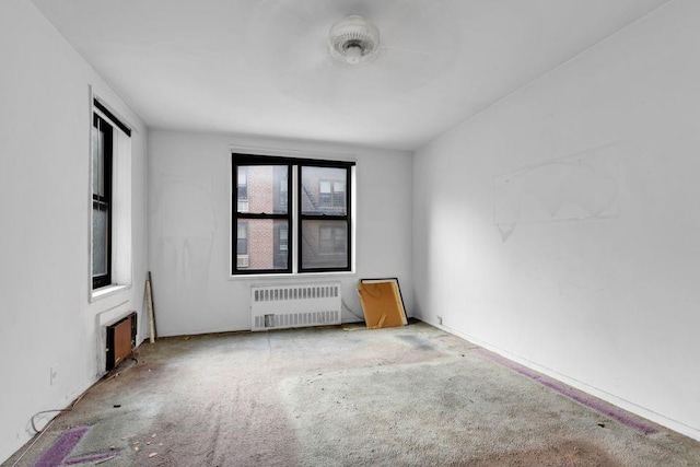 unfurnished room with radiator and carpet flooring