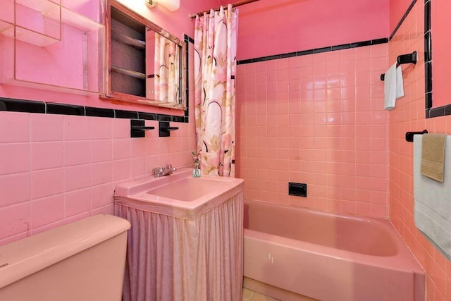 full bathroom with shower / bath combo, tile walls, toilet, and vanity