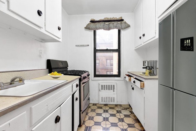 kitchen featuring white cabinetry, refrigerator, stainless steel range with gas cooktop, and sink