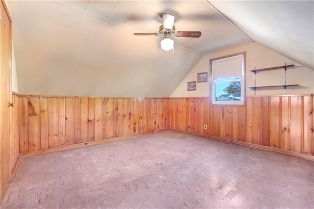 bonus room featuring wooden walls, ceiling fan, and vaulted ceiling