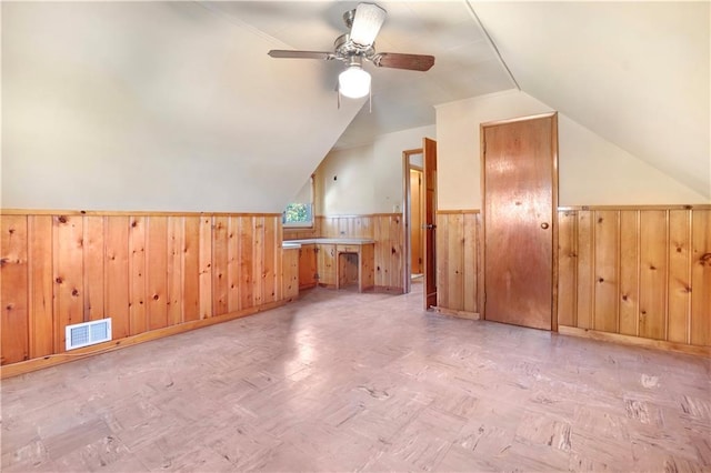 additional living space featuring ceiling fan, wooden walls, and vaulted ceiling