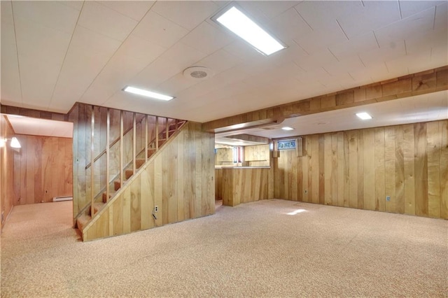 basement featuring carpet floors, a baseboard radiator, and wooden walls