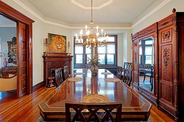 dining space featuring a fireplace, wood-type flooring, crown molding, and a wealth of natural light