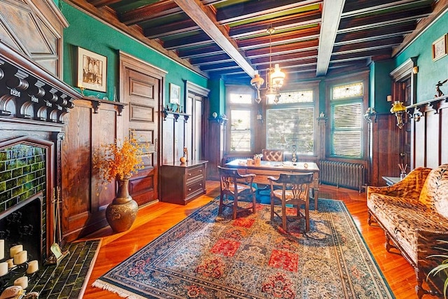 interior space featuring beam ceiling, radiator heating unit, wood-type flooring, and a notable chandelier