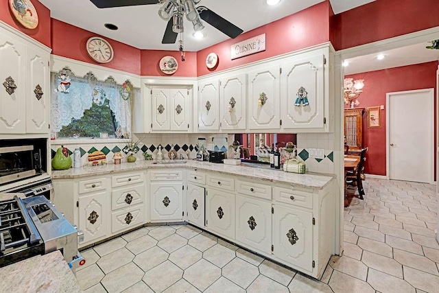 kitchen with white cabinetry, sink, light stone countertops, decorative backsplash, and ceiling fan with notable chandelier