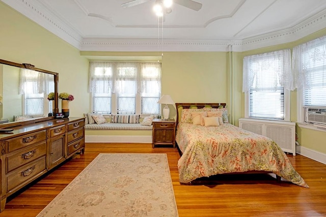 bedroom with radiator, ceiling fan, hardwood / wood-style floors, and crown molding