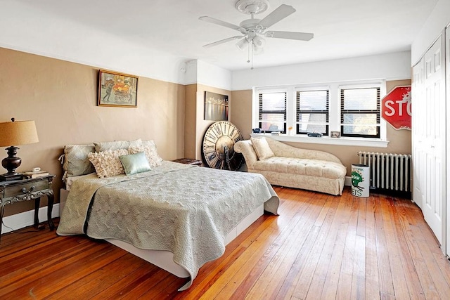 bedroom with hardwood / wood-style floors, ceiling fan, radiator, and a closet