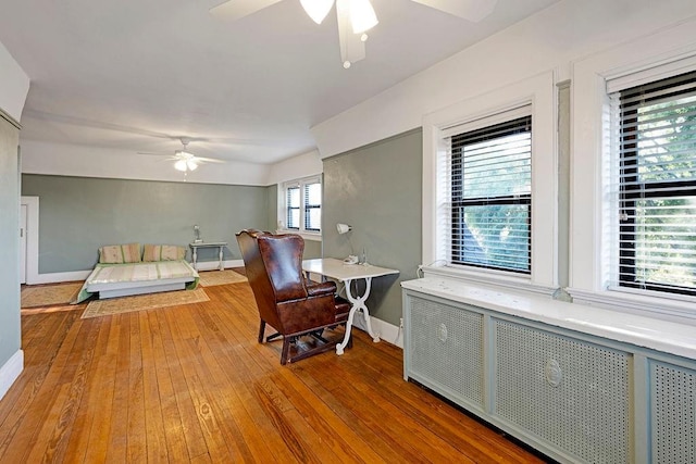 bedroom with radiator heating unit, light wood-type flooring, and multiple windows