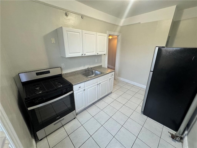 kitchen featuring stainless steel stove, black fridge, white cabinetry, and sink