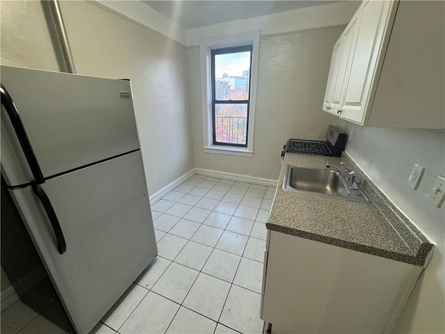 kitchen with light tile patterned flooring, white cabinetry, stainless steel refrigerator, and sink