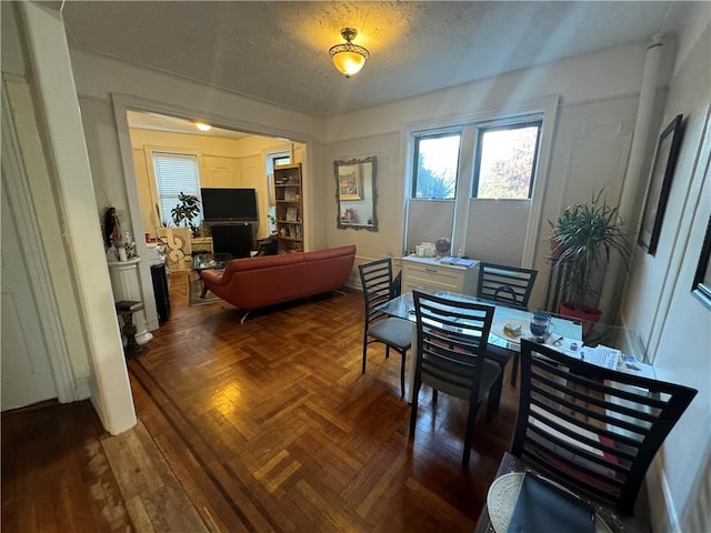 dining space featuring a textured ceiling and parquet flooring