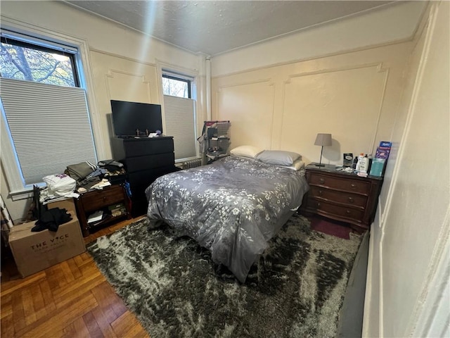 bedroom featuring multiple windows and parquet floors