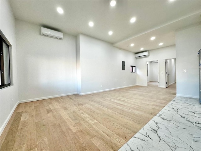 unfurnished room featuring a wall mounted AC, recessed lighting, light wood-type flooring, and baseboards