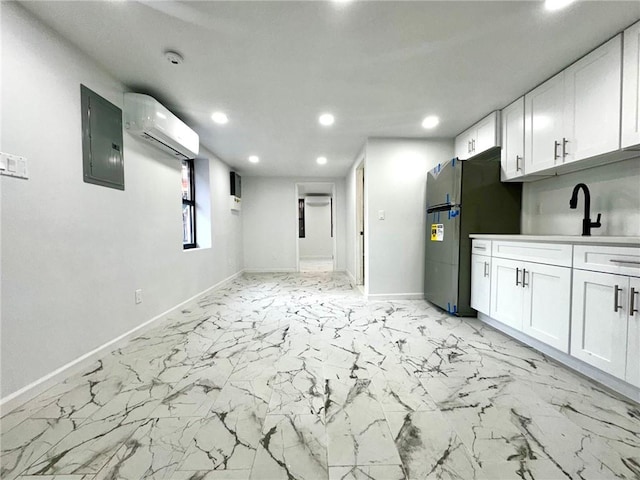 kitchen with recessed lighting, baseboards, white cabinetry, a wall mounted AC, and light marble finish flooring